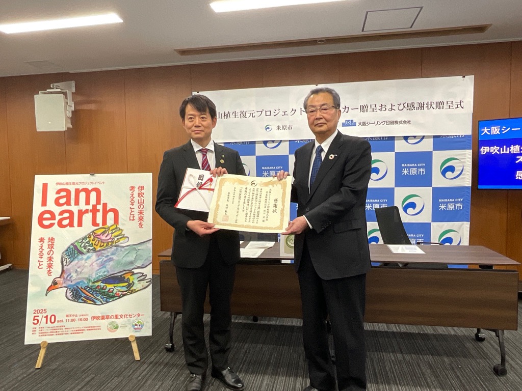 感謝状贈呈の写真。市長と男性の方が感謝状を手に持っている。
