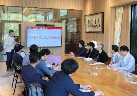 部屋の中央で並んでる机の横に小さなテレビで「人材誘致による地方創生」と書いてある映像を流しながら、淡路島の方が説明を行っているようす