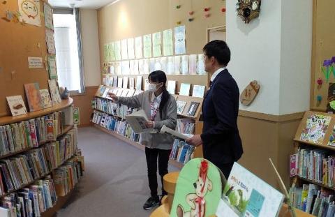 近江図書館の視察風景。本棚に向かって説明している職員と市長の写真。
