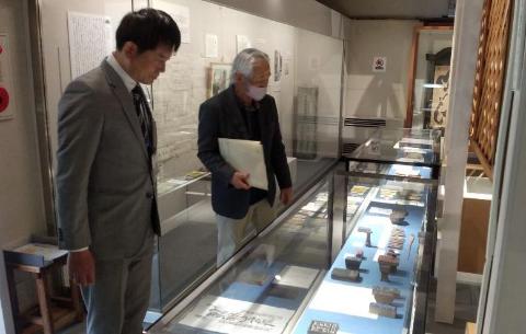 柏原宿歴史館視察風景。ガラスケースに入っている資料物などを説明されている職員と市長の写真