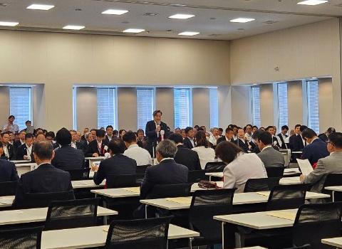 会議室で、長机で囲んで、中央あたりに1人の男性がマイクを手に持ちお話されているようす