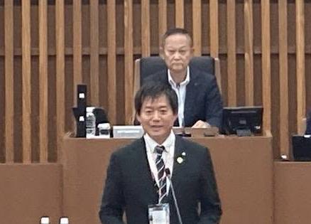 議場にてお話されている市長と、後ろに議長が着席しているようすの写真。
