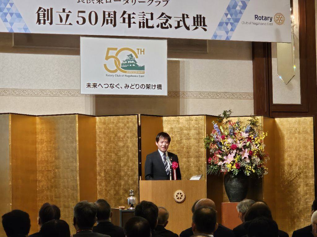 背後に金屏風があり、壇上にて挨拶されている市長の写真