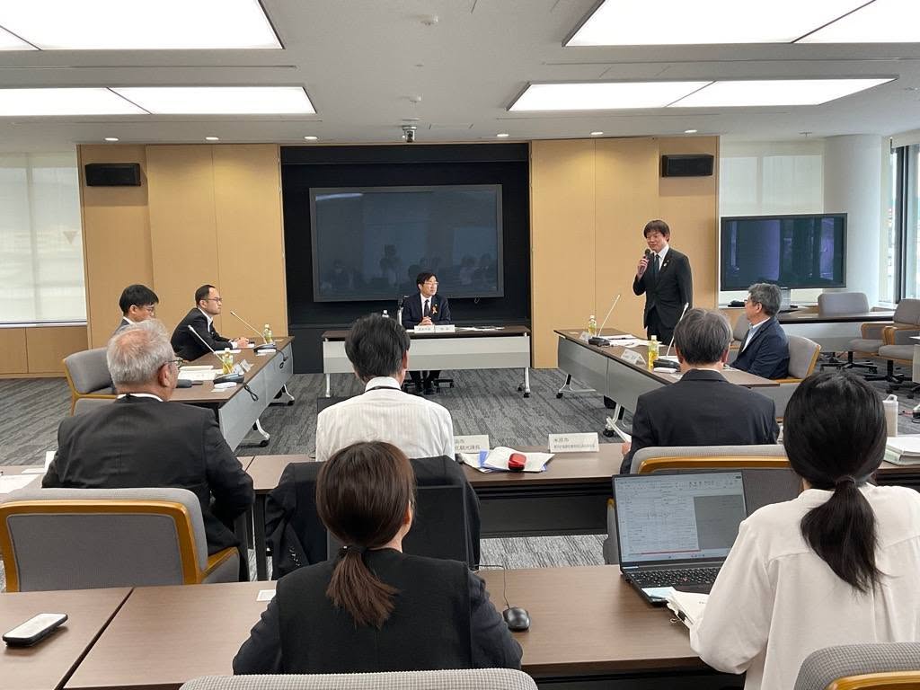 会議室にて、マイクを手に持ち立って意見を述べている市長の写真