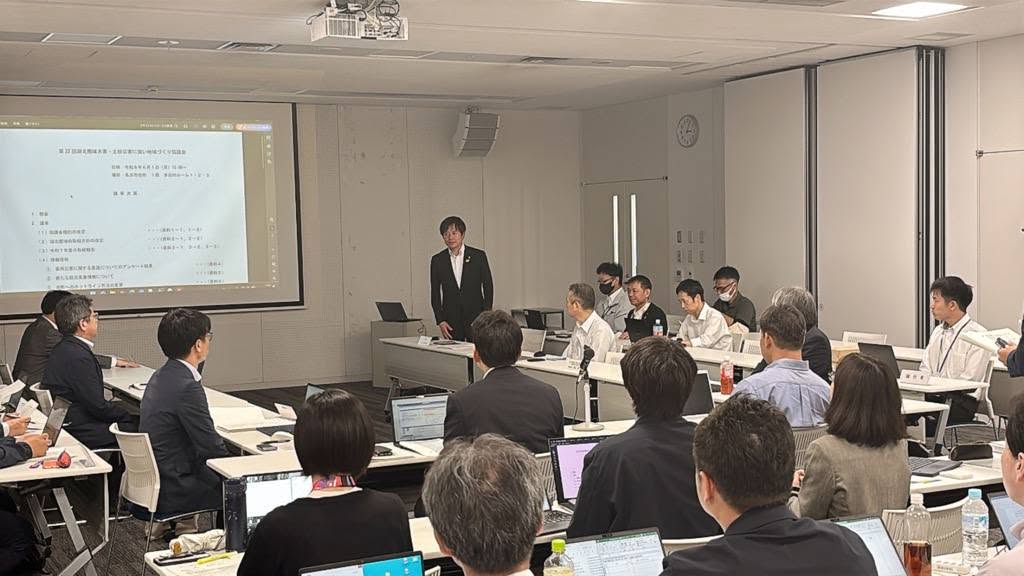 会議室にて長机で囲んで、立ってお話されている市長の写真
