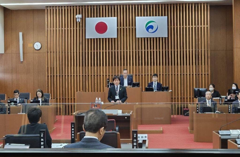 議場にてお話されてる市長の写真。周りには議員、市職員が着席しているようすの写真。