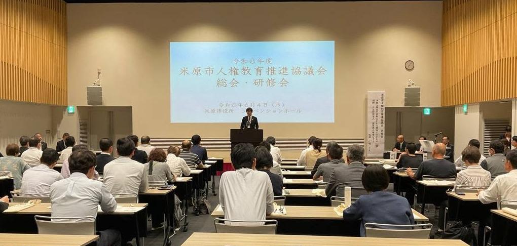コンベンションホールにて、参加者たちの前でお話されてる市長。後ろにはプロジェクタースクリーンがかかっている。