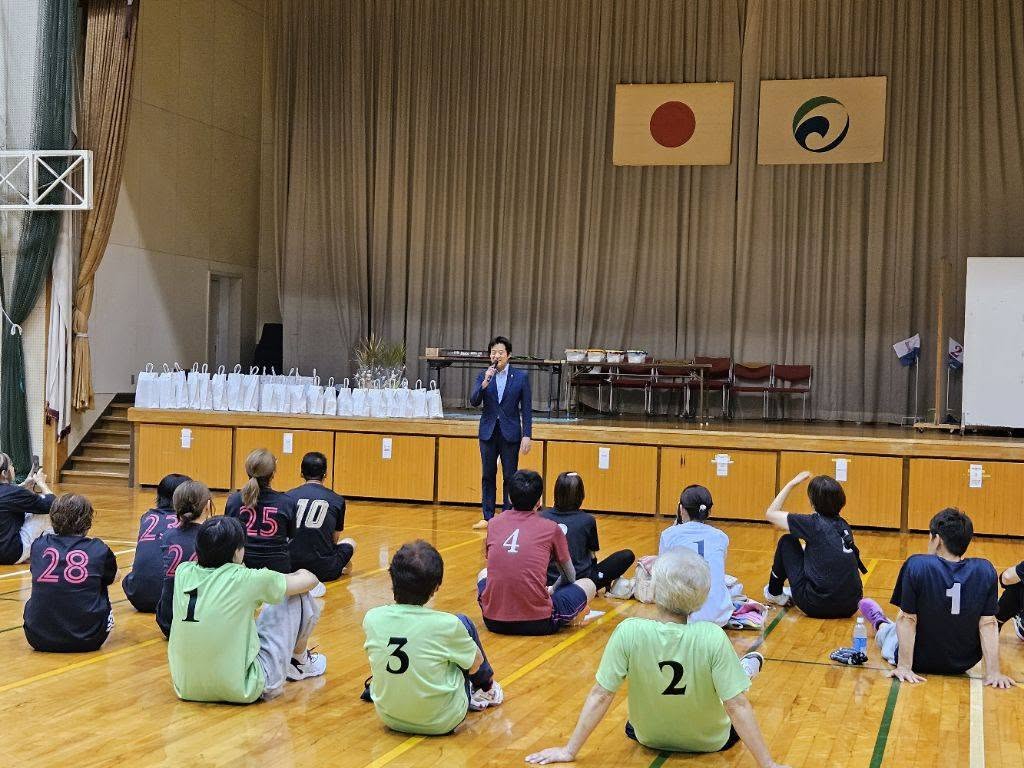 体育館にて、参加者の皆さんの前でお話されている市長の写真