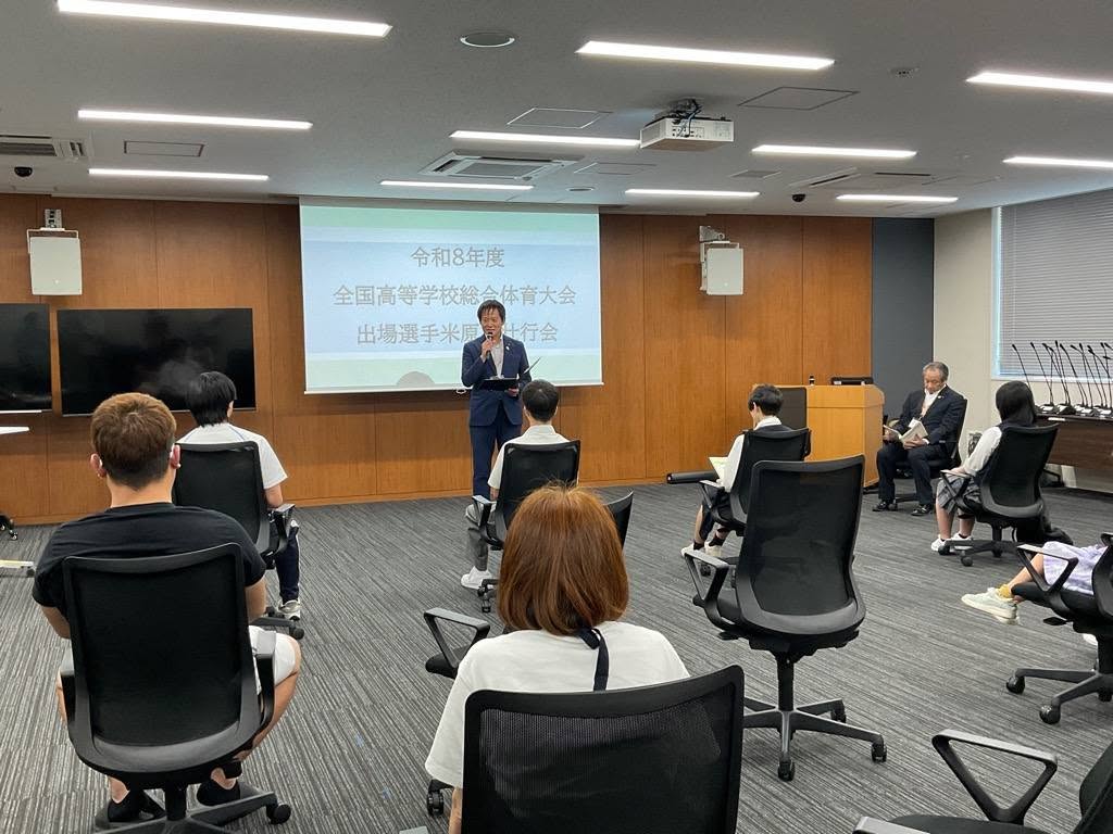 会議室にて、マイクを手に持って激励のことばを送っているようす