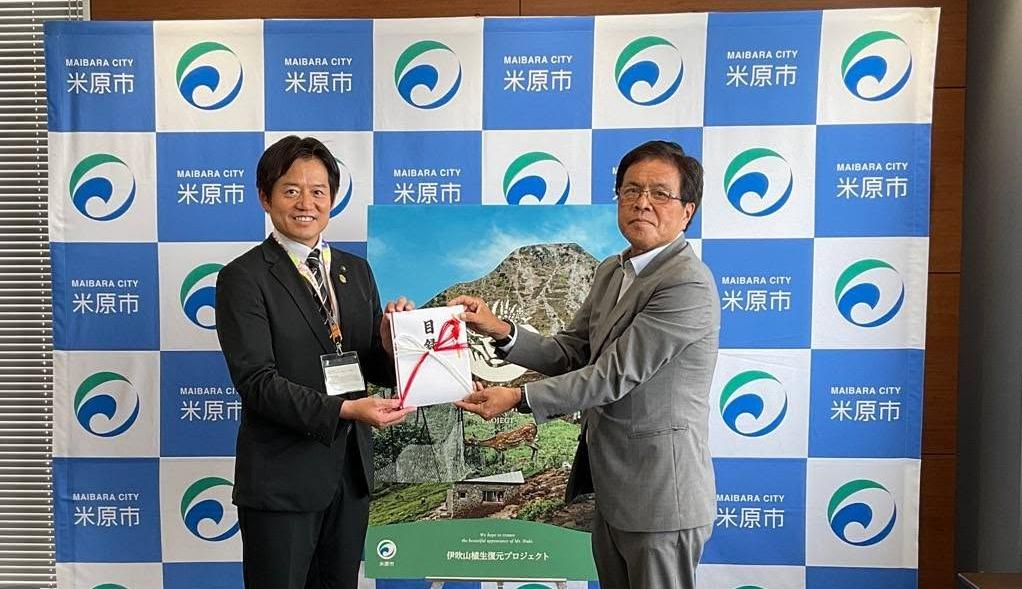 市長と伊吹電業株式会社の方2人で目録を手に持っている写真