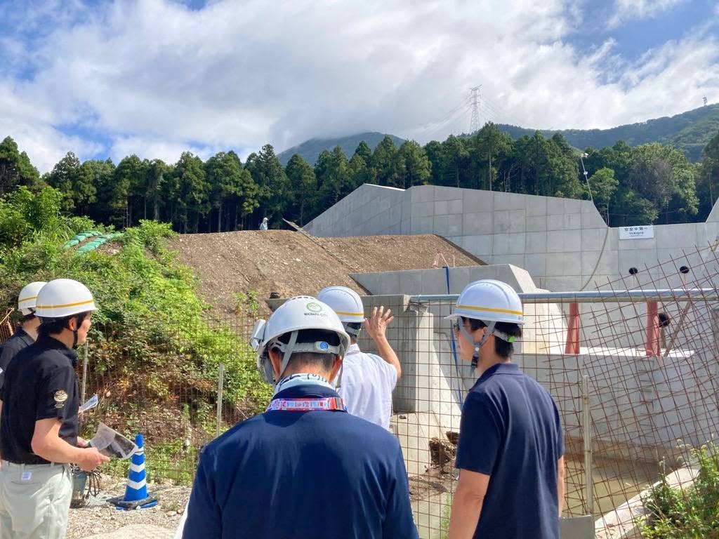 ヘルメットを被った複数の職員が、勝山谷川の砂防堰堤を視察している写真
