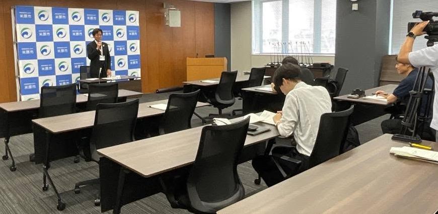 定例記者会見にてお話されている市長の写真。写真右側にはカメラが設置されている。