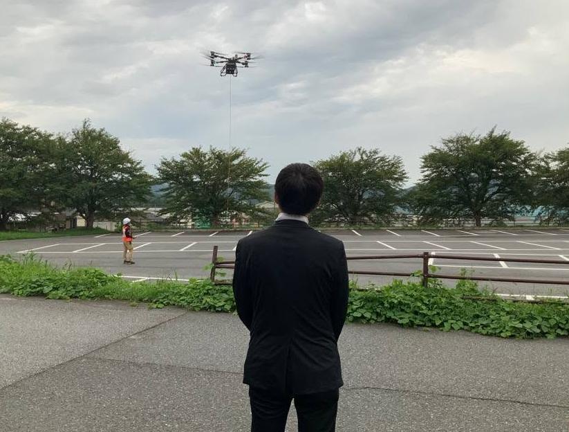 機材お披露目で、空飛ぶドローンを見つめる市長の写真