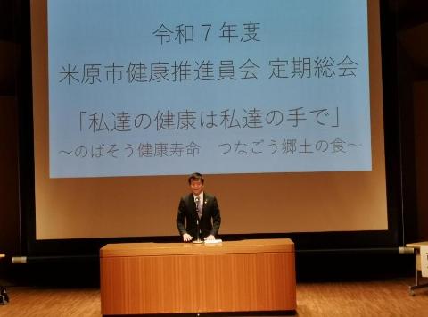 大きなプロジェクターの前で市長が挨拶をされている写真
