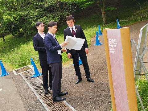 国営昭和記念公園での視察風景。資料を手に説明をしている職員と市長の写真