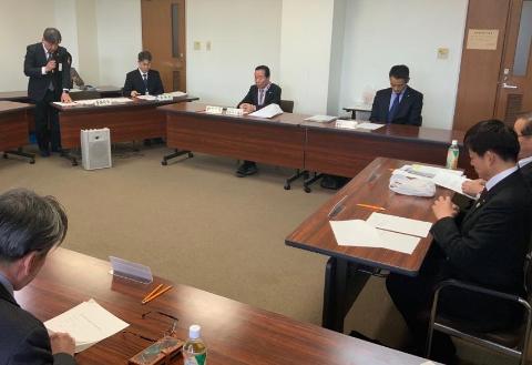 会議室でマイクを持った男性が立って説明をしている写真