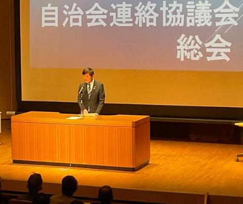 ステージの上で、卓上マイクで挨拶されている市長の写真