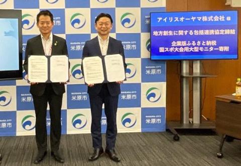 左から市長、アイリスオーヤマ株式会社の方とそれぞれ手に書類を手に持って撮影されている。その横には寄付いただいた、国スポ大会用大型モニターが設置されている。