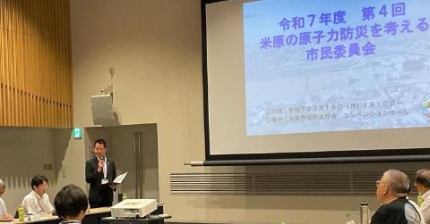 プロジェクタースクリーンが後ろにあり、マイクを手に持ち話をされている市長の写真