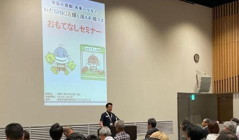 後ろに大きなプロジェクタースクリーンがあり、壇上でお話されている市長の写真