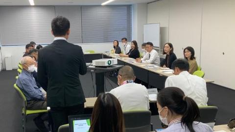 会議室にて長机で囲んで、立ってお話されている市長の写真