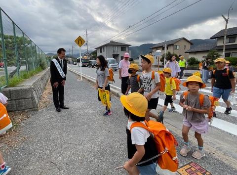 横断歩道を渡り終えた、登校中の子どもたちに挨拶する市長の写真