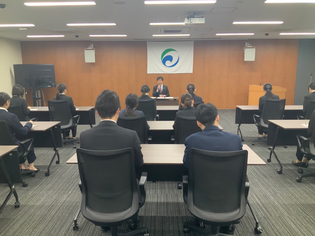会議室にて職員の皆さまの前で講話を行っているようす