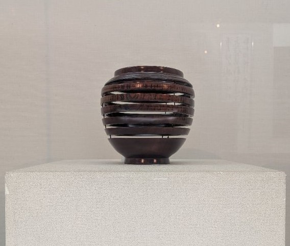 深い茶色の壺で、輪切りされたような隙間がある。