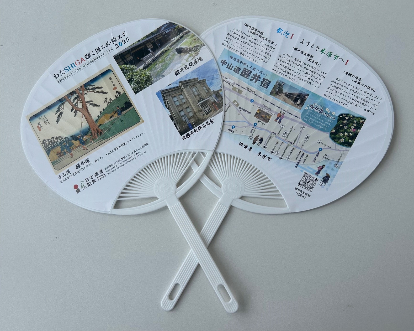 国スポ障スポ2025開催に伴い作成された2枚のうちわ。うちわの表は醒井宿の絵や旧醒井郵便局局舎の写真等が掲載されている。うちわの裏は、醒井宿周辺のマップイラストと解説が掲載されている。