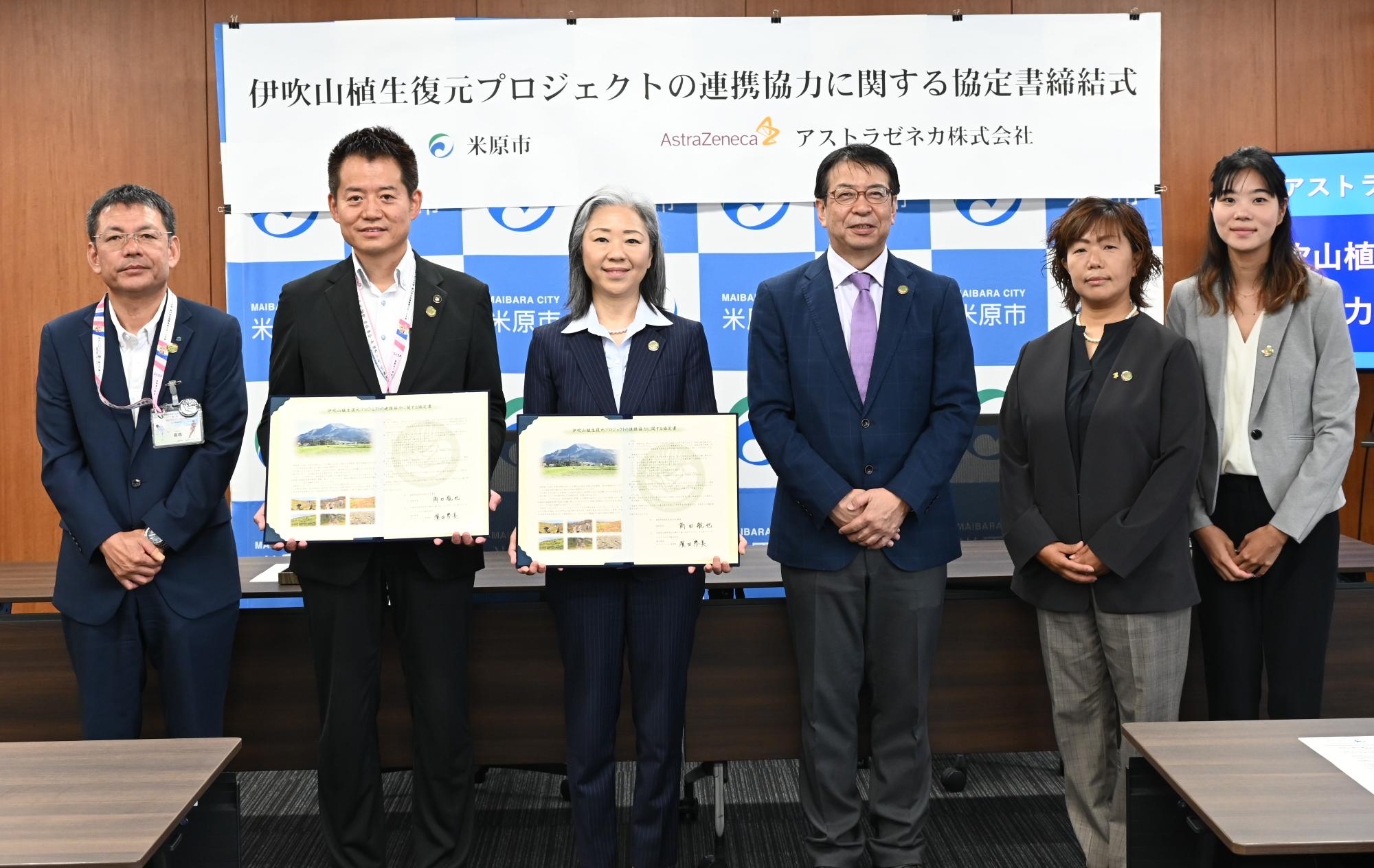 協定締結所をもつ角田市長とアストラゼネカオペレーション本部長濱田琴美氏。他関係者4名の記念写真