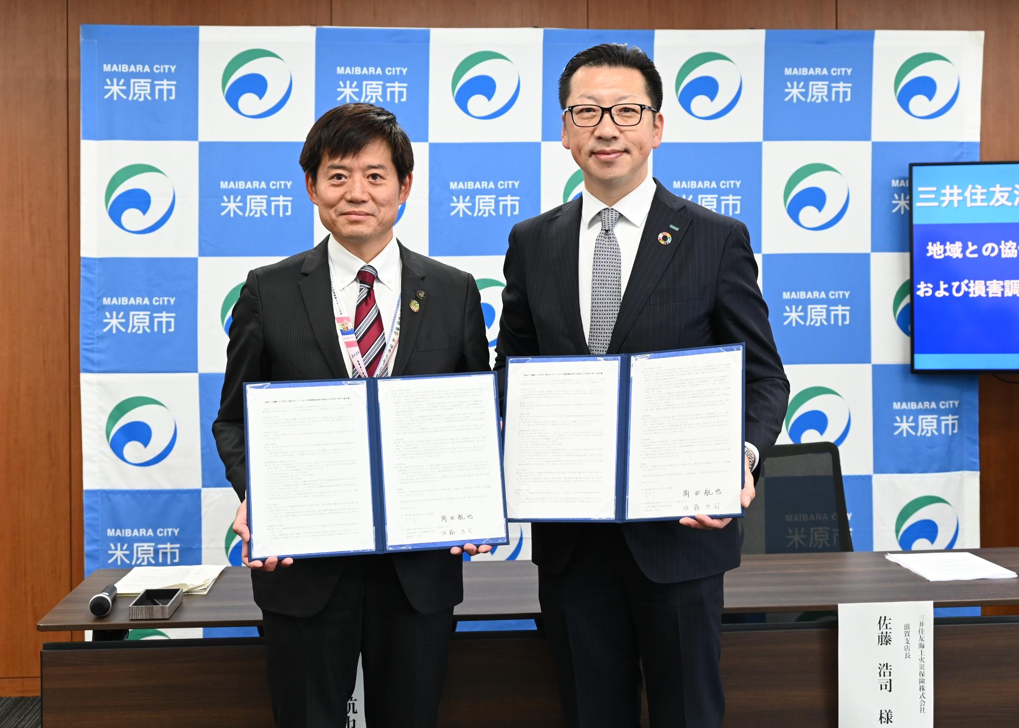 左側に協定書を持つ角田市長と、右側に協定書を持つ三井住友海上火災保険株式会社の佐藤浩司滋賀支店長