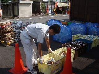 コンテナに入った廃食用油を回収している男性の写真