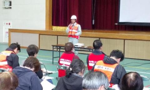 体育館にて、ヘルメットを着用し挨拶をされている市長の写真