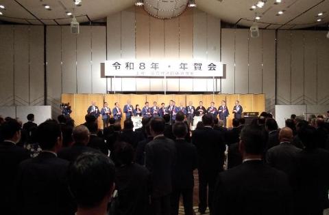 年賀会の風景。壇上の後ろには金屏風がある。