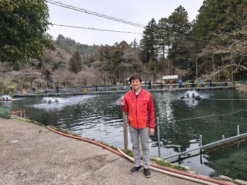 醒井養鱒場の前でポーズをとって撮影している市長の写真