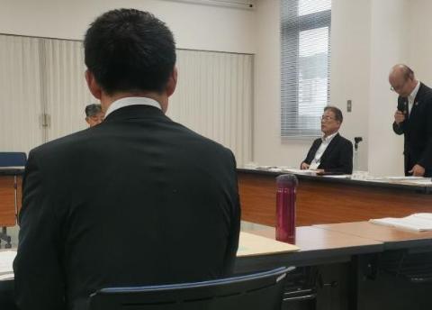 会議室で、長机で囲んで、奥の方にマイクを手に持ちお話されている方、手前に座っている市長の写真