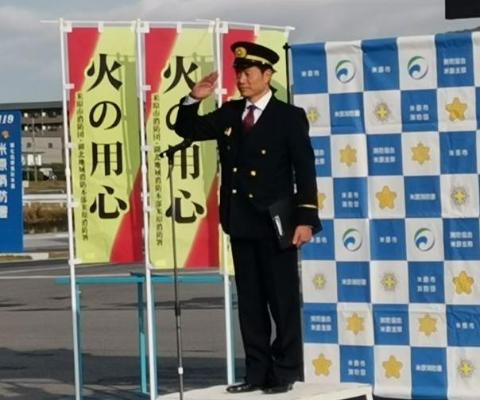 火の用心とかかれているのぼりの前で、団員の皆さまにむけて敬礼する市長の写真