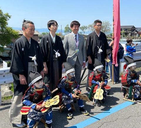 参加者との記念撮影。着物を着ている男性3人と武者姿の子どもたちと囲んで撮影されているようす