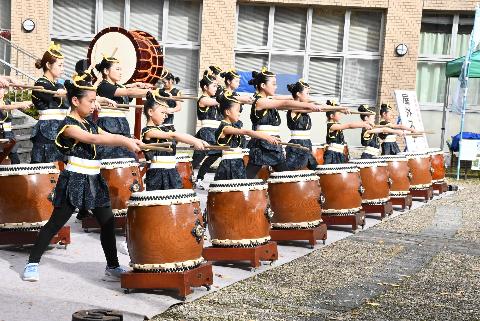 屋外ステージにて、ほたる太鼓保存会による太鼓パフォーマンスを行っているようす
