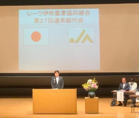 後ろに大きなプロジェクタースクリーンがあり、壇上で挨拶をされている市長の写真