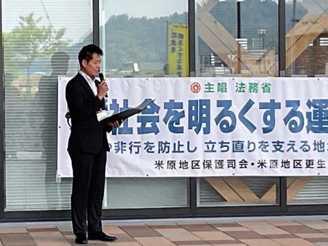 社会を明るくする運動のスローガンが後ろにあり、マイクを手に持ち挨拶されてる市長