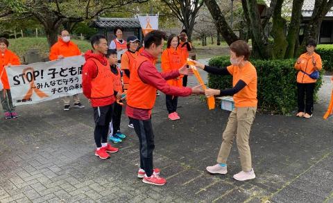オレンジ色のたすきを次の選手に手渡しているようす