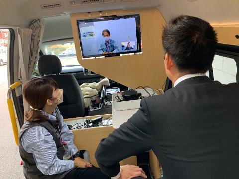 移動市役所室内では、運転手席の後ろにモニターがあり遠隔操作で市民とお話するシステムとなっている。それを体験している市長の写真