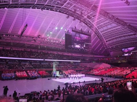 観客席には大勢の観客がおり、体育館の中心には各国の選手たちがあつまっているようす