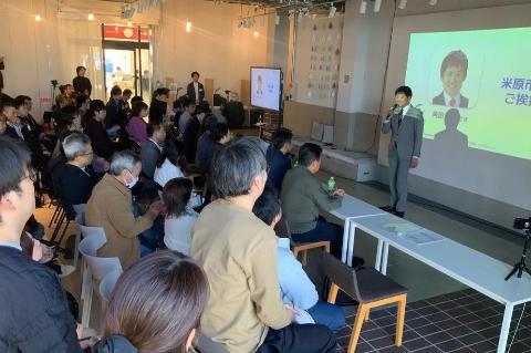 プロジェクタースクリーンの前で挨拶する市長の写真