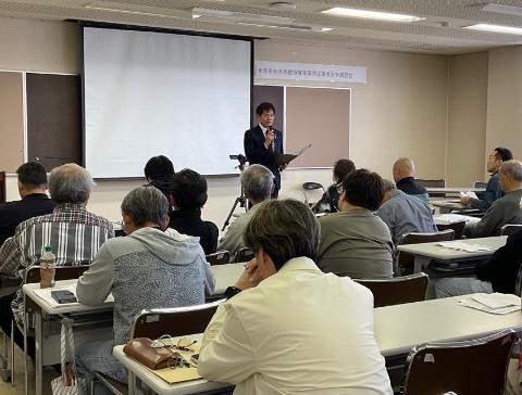 会議室にてプロジェクタースクリーンの前で挨拶されている市長の写真