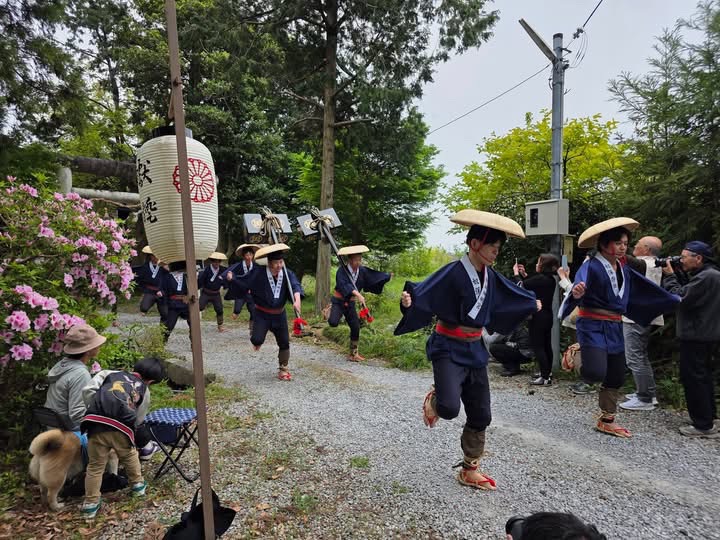 蹴り奴振りのようす。三度笠を被って作務衣を着ている男性の集団が片足あげて移動しているようす