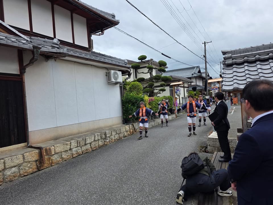 公家奴振りのようす。真ん中にオレンジ色のタスキがある法被を着ている男性の集団が練り歩いているようす