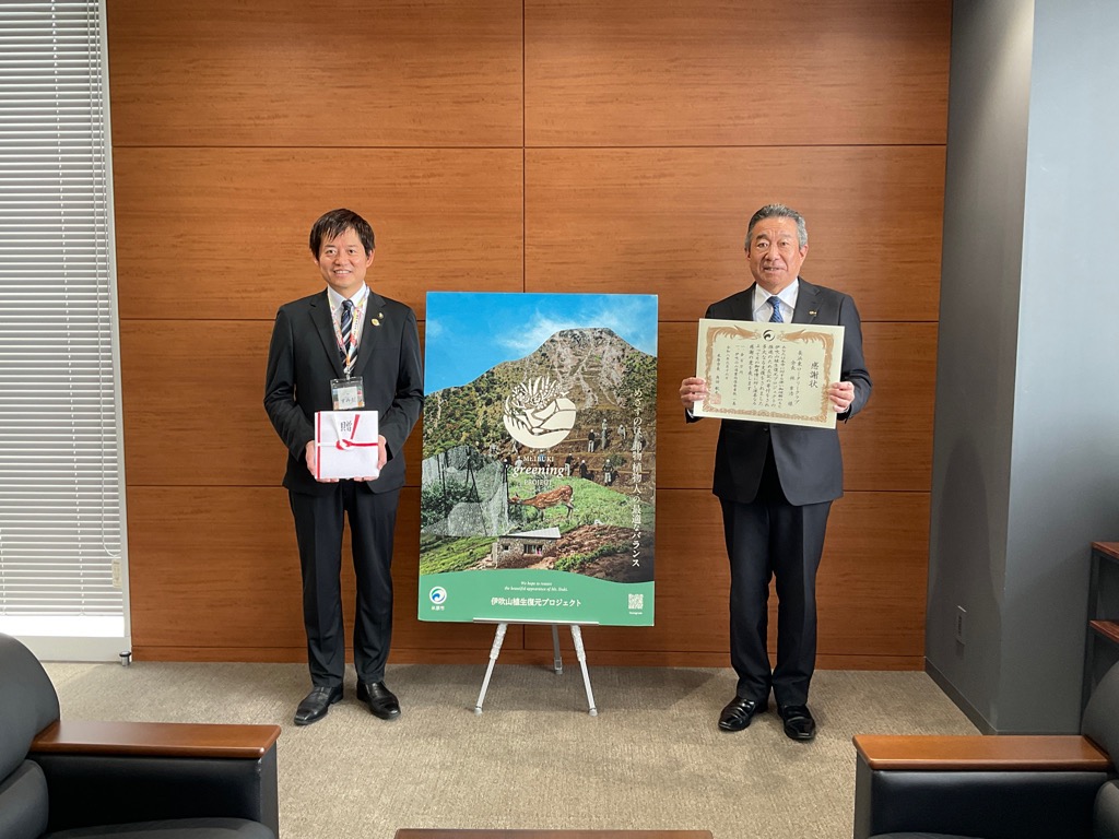 左から寄付金封筒を手に持っている市長、その横には伊吹山植生復元プロジェクトを掲げたパネル、その横には感謝状を手に持っている長浜東ロータリークラブの男性の写真