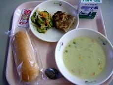 黒糖パン、グリーンポタージュスープ、豆腐入りミートローフ、ケチャップ、野菜サラダ、牛乳がトレーに並べられた写真